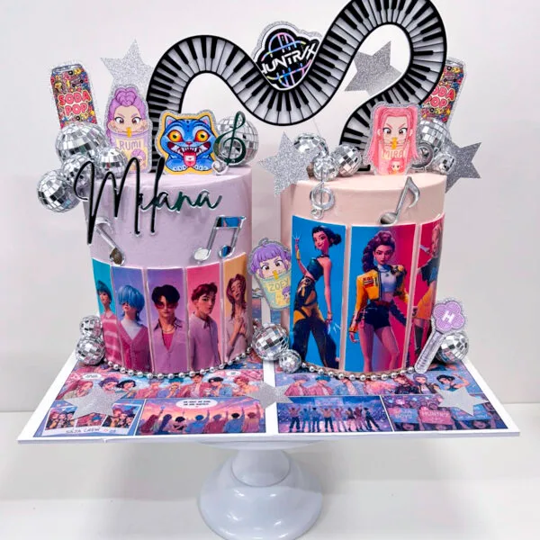Shop 328 Joint Kpop Demon Hunters Cake Birmingham — black and pink cake with acrylic piano keys, comic character toppers and disco ball details, handmade by Khalid's Kakes