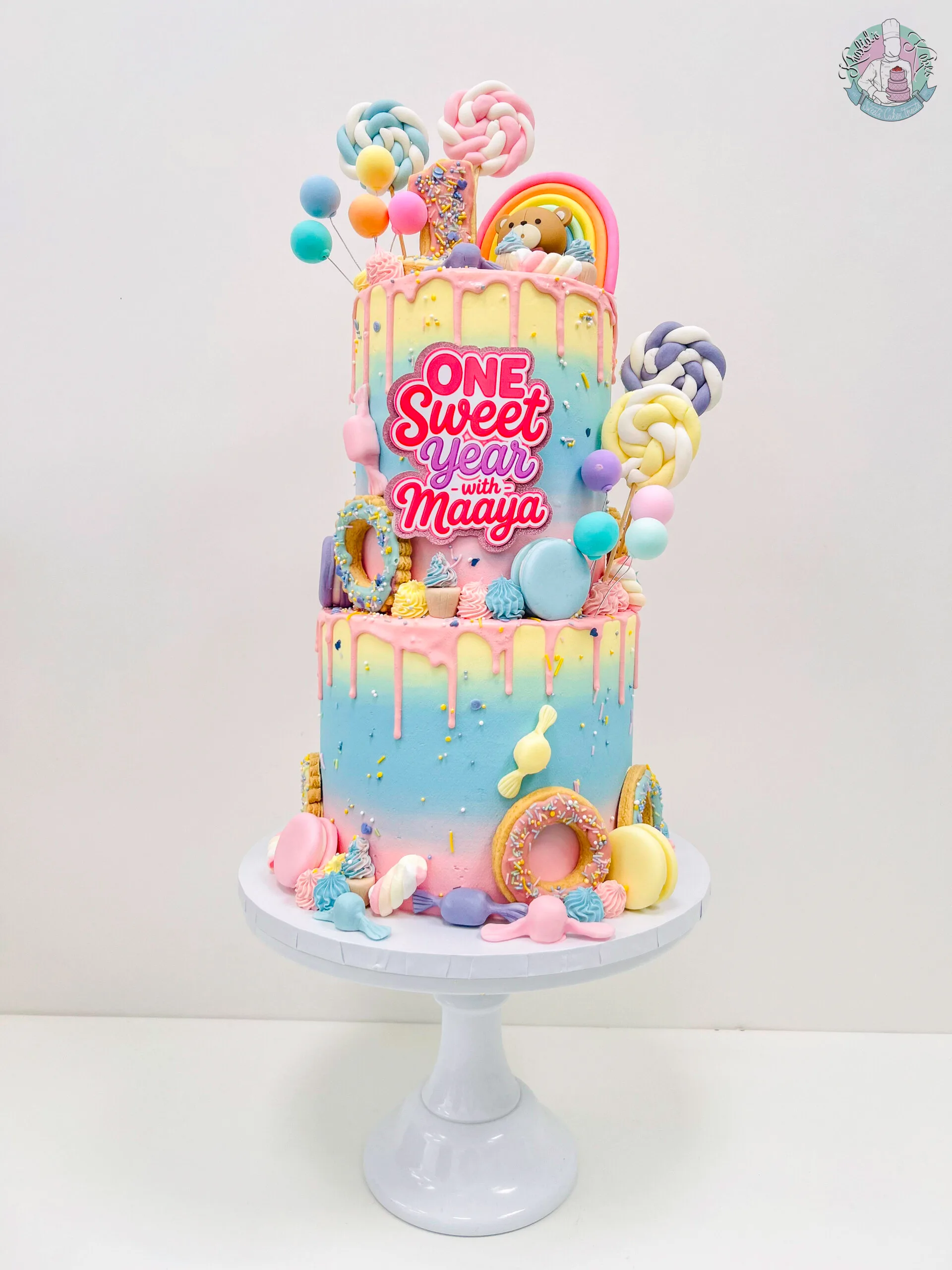 One Sweet Year birthday cake Birmingham — pastel ombré drip cake with mini doughnuts, rainbow topper and sprinkles, handmade by Khalid's Kakes