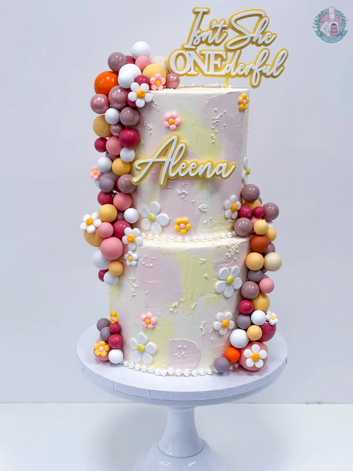 Daisy ONEderful Cake Birmingham — pastel two-tier 1st birthday cake with daisy flowers and a gold topper, handmade by Khalid's Kakes